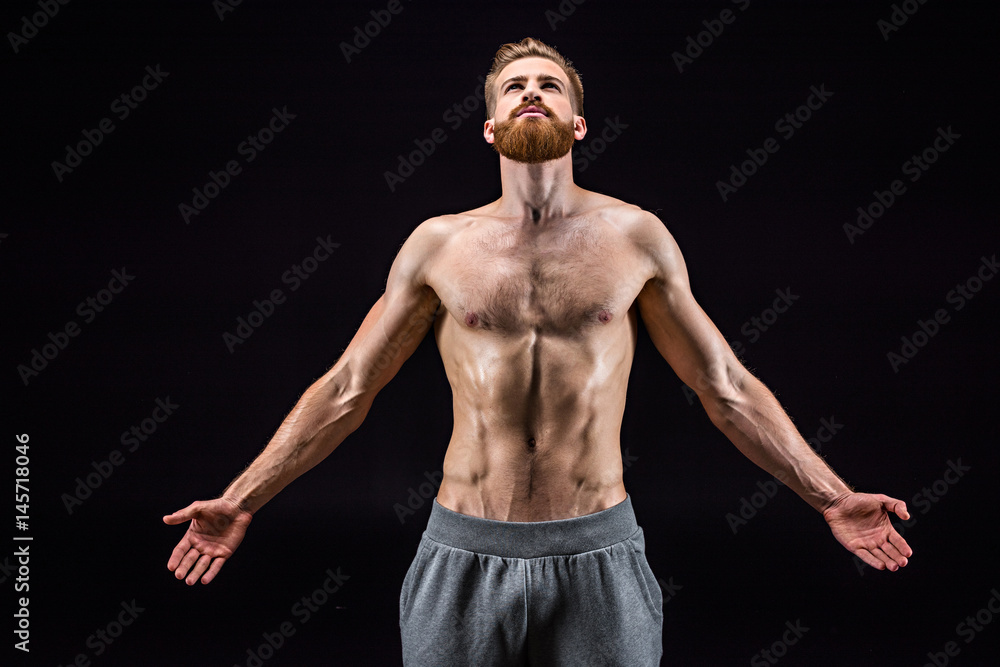 shirtless bearded bodybuilder posing isolated on black in studio