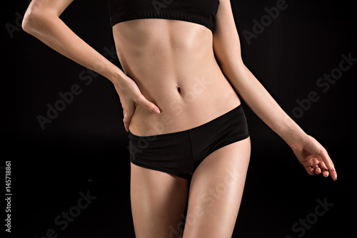 cropped view of sportswoman in black underwear isolated on black © LIGHTFIELD STUDIOS