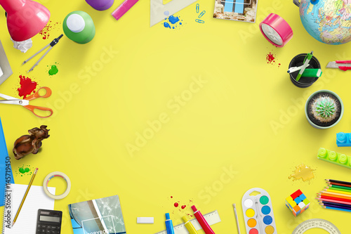 Yellow school work desk with creative, fun items beside. Free space in middle for text.