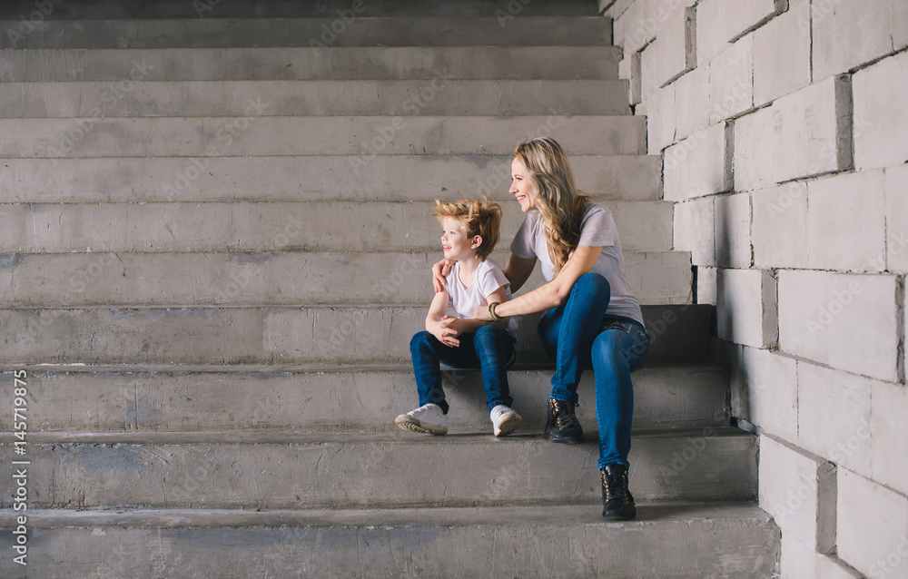 Mother with son sitting on a stairs and looking somewhere Mother with son sitting on a stairs and looking somewhere
