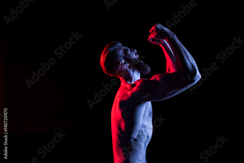 handsome bodybuilder gesturing and yelling isolated on black with dramatic lighting
