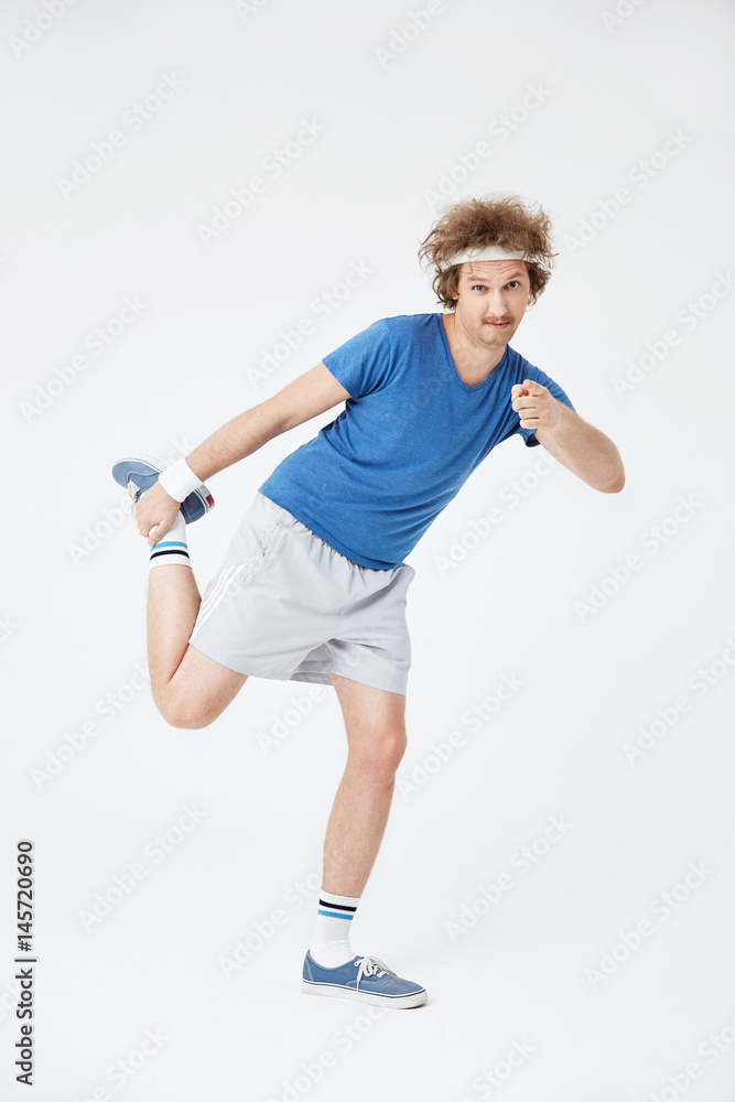 Retro guy stretching right leg holding foot with right hand Retro guy stretching right leg holding foot with right hand
