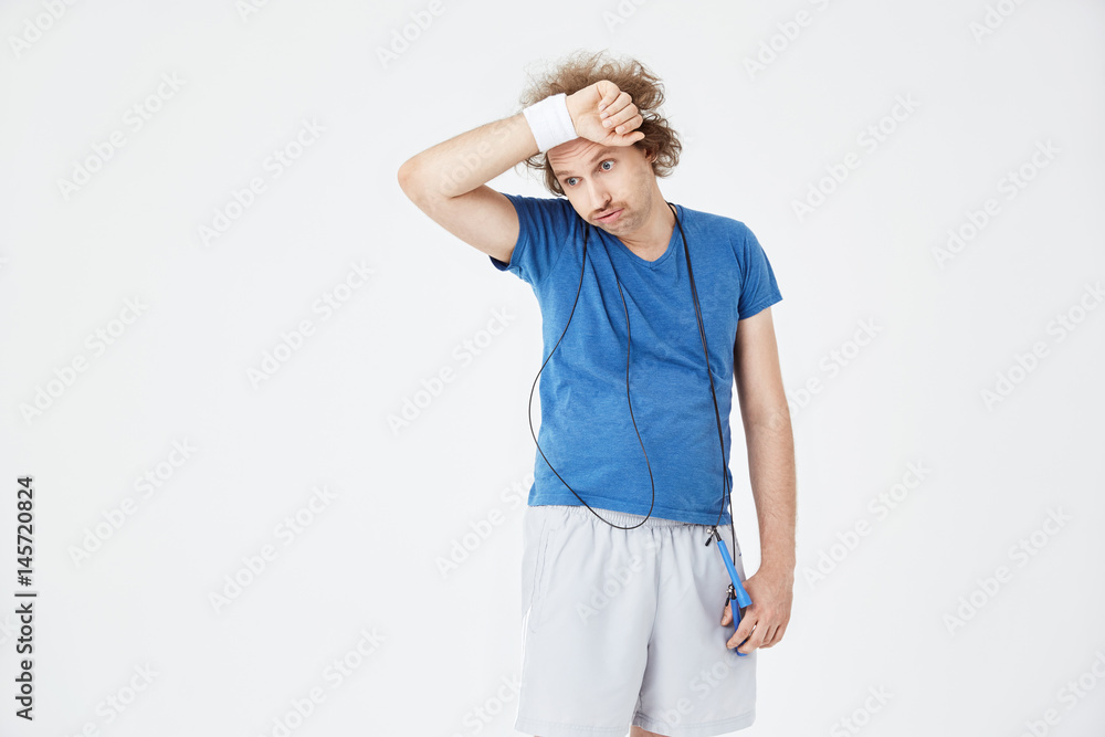 Exhausted man mopping his brow with sweatband after training Exhausted man mopping his brow with sweatband after training
