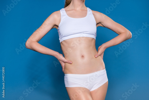 mid section view of young sportswoman in white underwear isolated on blue © LIGHTFIELD STUDIOS