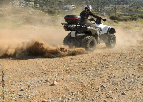 A man riding ATV in sand in a  helmet. © Paopano