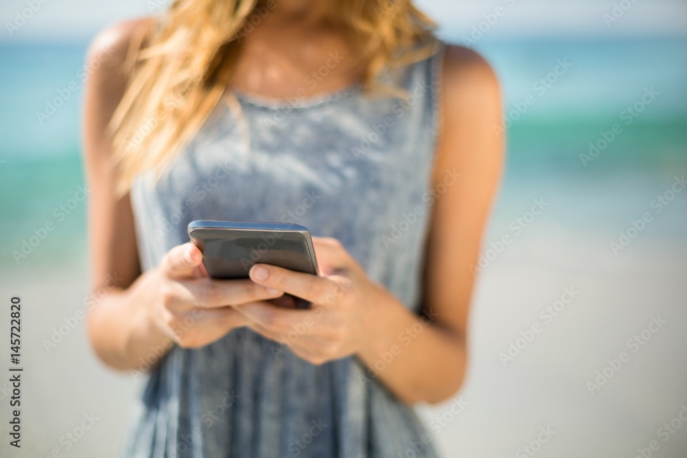 Midsection of woman using mobile phone at beach Midsection of woman using mobile phone at beach