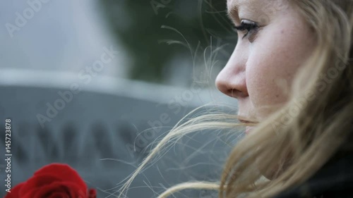slow motion somber girl with rose visits gravestone in cemetery