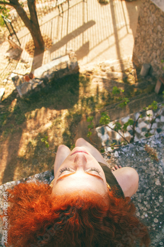 Vista desde arriba de una mujer joven disfrutando del sol y la brisa en verano  photo