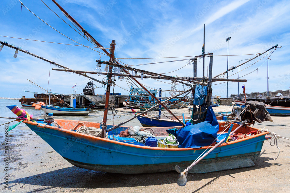 Fishing boats aground on the beach over cloudy sky at Prachuap Khiri Khan, Thailand.