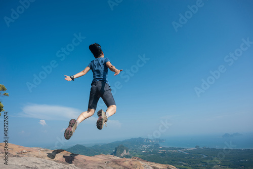 jumping on rocky mountain peak, freedom, risk, challenge, success concept