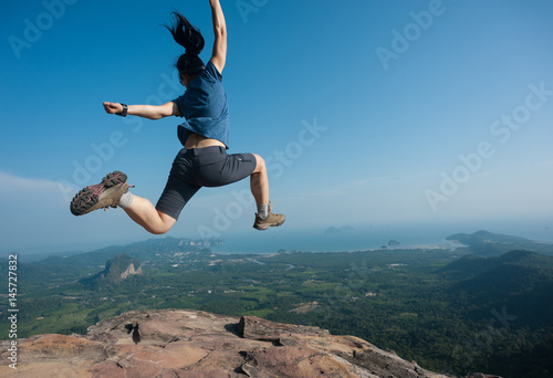 jumping on rocky mountain peak, freedom, risk, challenge, success concept