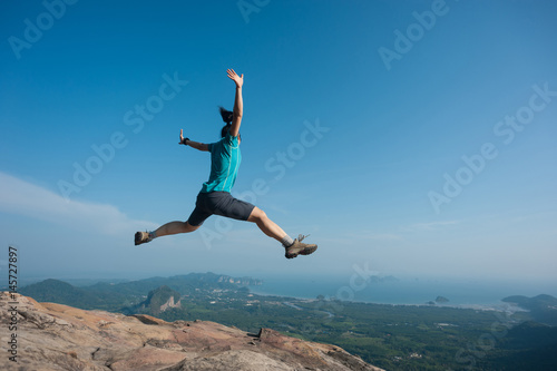 jumping on rocky mountain peak, freedom, risk, challenge, success concept