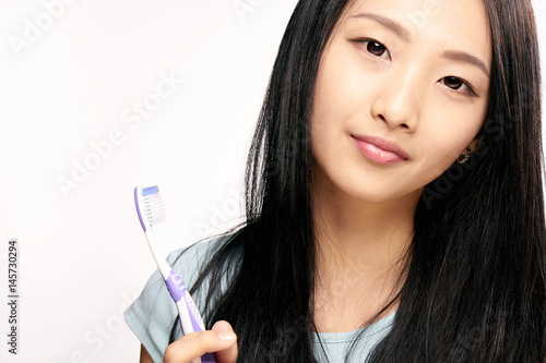 pretty woman with a purple toothbrush on a light background