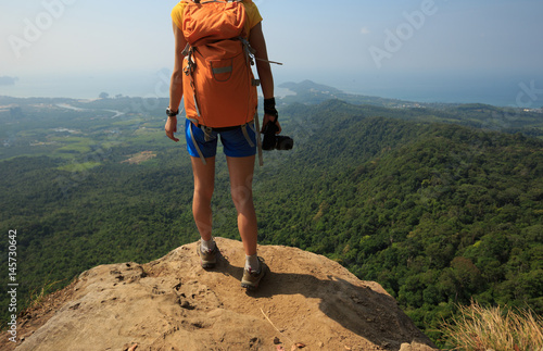 successful woman photographer on mountain peak cliff