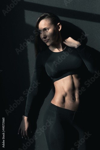 Young fitness woman in sportswear posing and looking away