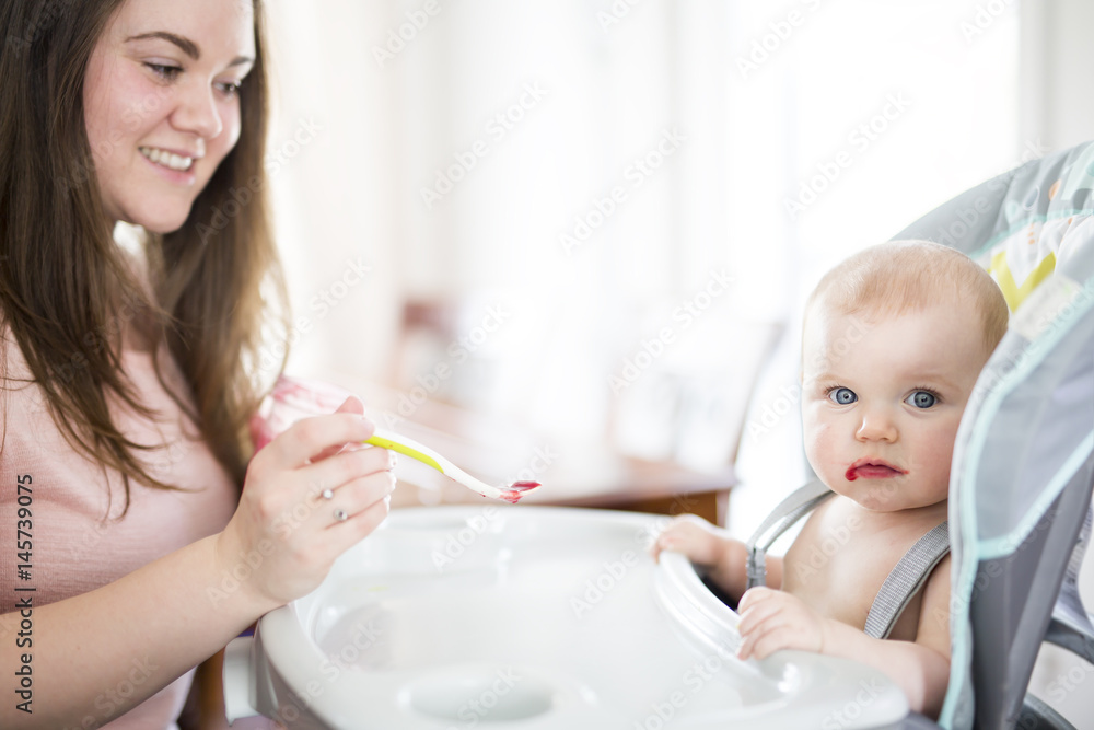 Mother Feeding Baby girl In High Chair Mother Feeding Baby girl In High Chair
