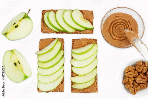 Sandwiches with peanut butter and an apple on the table close-up. Apple slices, walnuts isolated on white background. Horizontal top view.