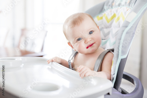 Baby girl sitting in high chair for eating