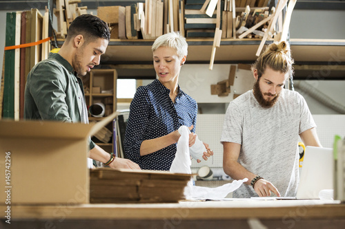 3 young people packing up products in a small warehouse