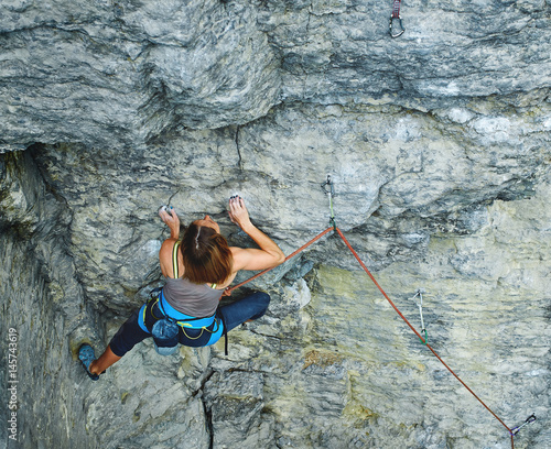 woman rock climber. rock climber climbs on a rocky wall. woman makes hard move