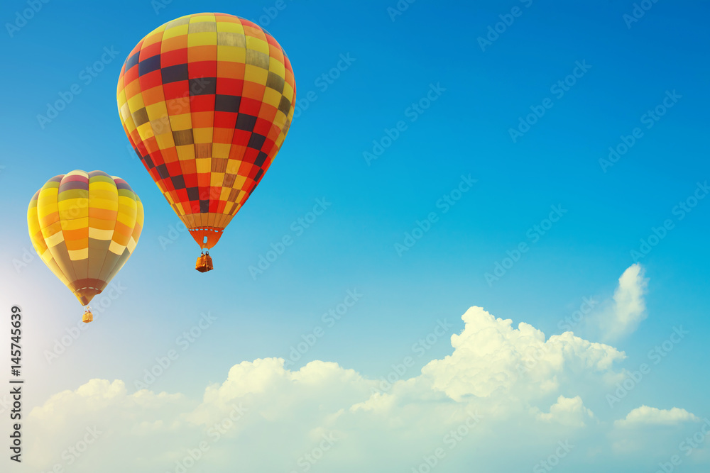 Fototapeta premium Two colorful hot air balloons up in the beautiful blue sky with cloud. Travel background concept with free space for text. Fresh nature and relax vacation.