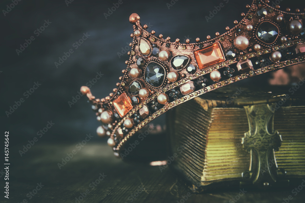 Obraz premium low key image of beautiful queen/king crown on old book