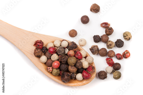 Mixture of peppers hot, red, black, white and green pepper in a wooden spoon isolated on white background. Top view