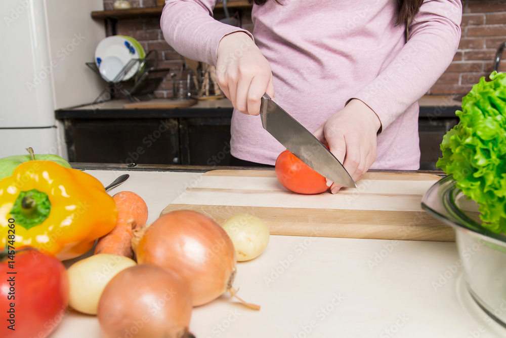 A woman cuts a cucumber in the kitchen with a knife. Preparation of salad and healthy food. Diet. A woman cuts a cucumber in the kitchen with a knife. Preparation of salad and healthy food. Diet.