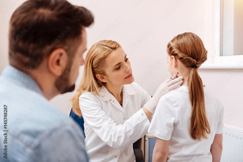 Serious pediatrician examining mole on the neck