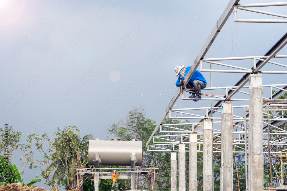 A construction workers installing beam formwork. Formwork is located at the high level that requires the workers to use scaffolding. A construction workers installing beam formwork. Formwork is located at the high level that requires the workers to use scaffolding.