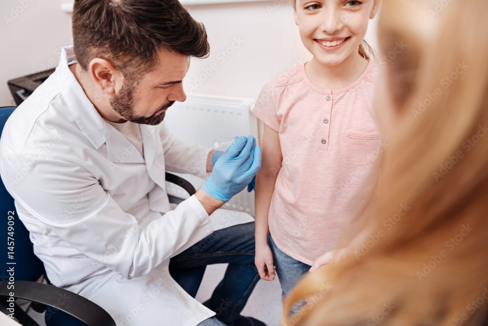 Fototapeta premium Competent doctor vaccinating little girl against season diseases