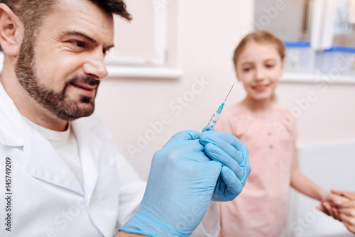 Portrait of smiling pediatrician holding syringe