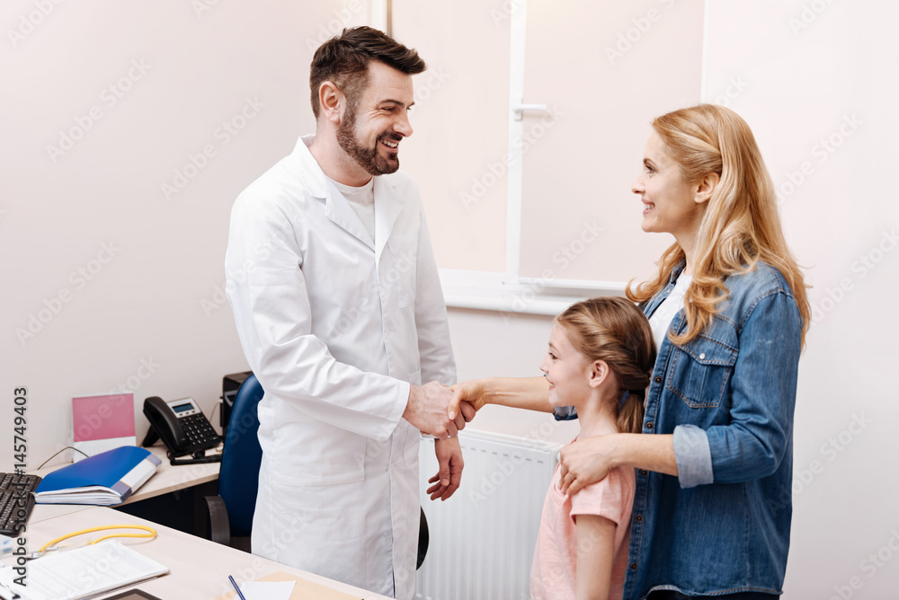Fototapeta premium Positive delighted doctor holding hand of his visitor