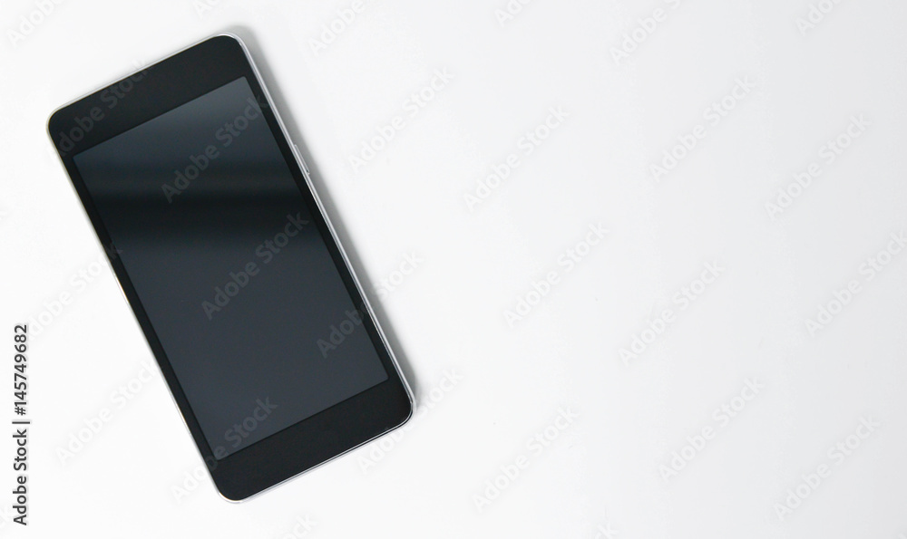 Naklejka premium Flat lay Black mobile phone on the white screen
