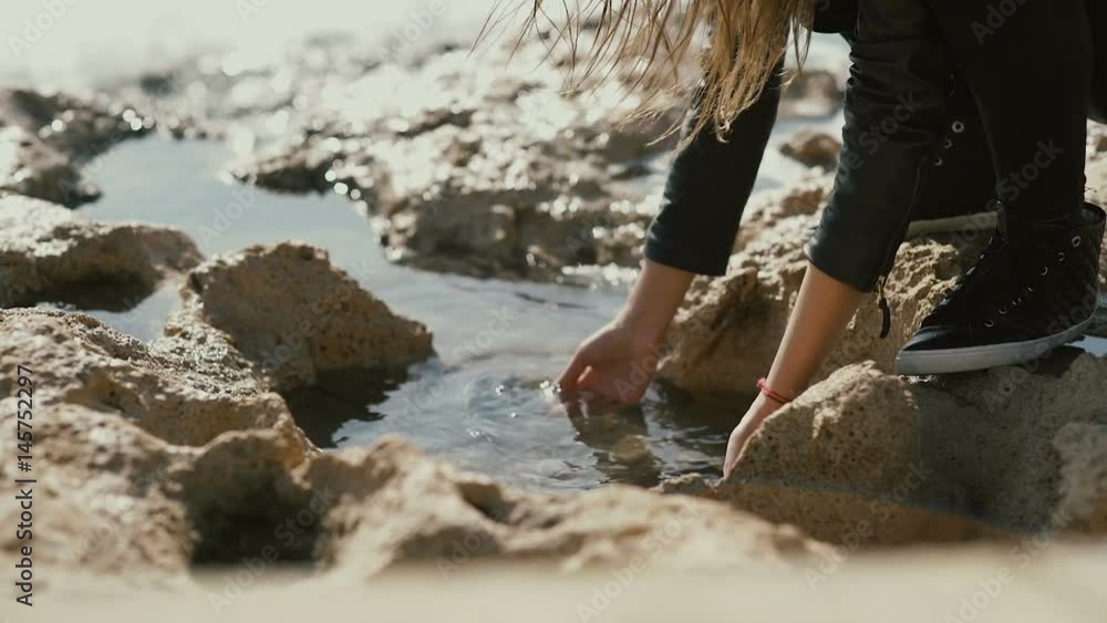 The girl dip her hands into the water on the coast of the sea The girl dip her hands into the water on the coast of the sea