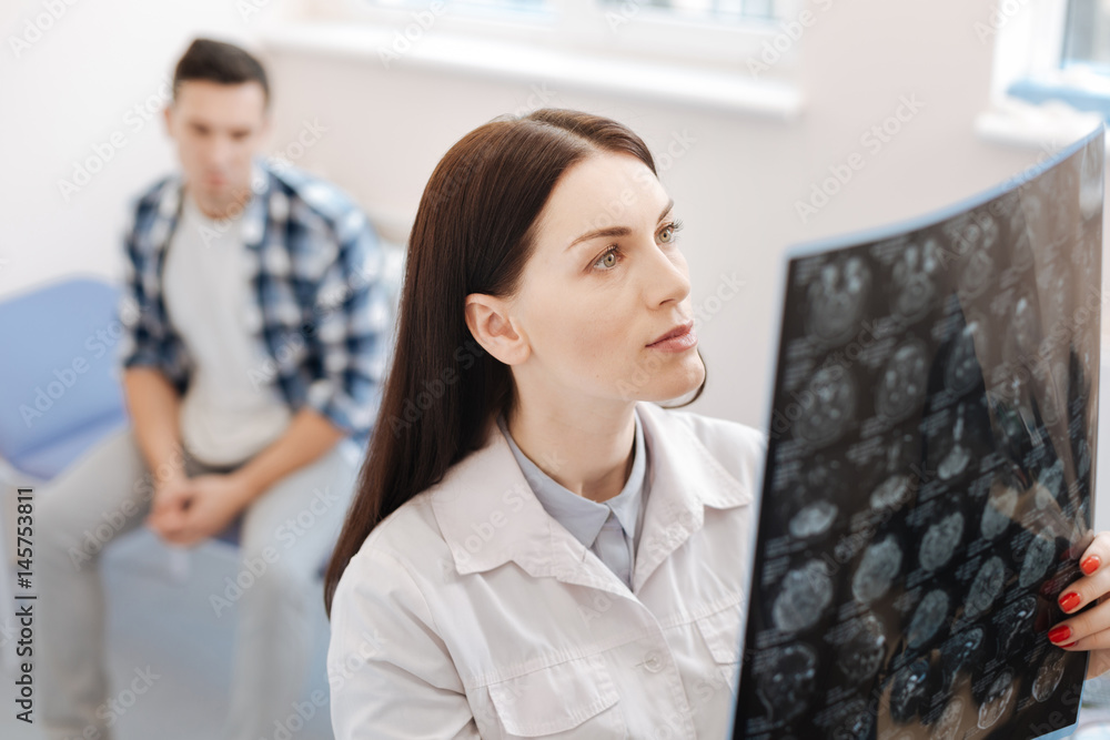 Serious female neurologist examining the X ray photo Serious female neurologist examining the X ray photo