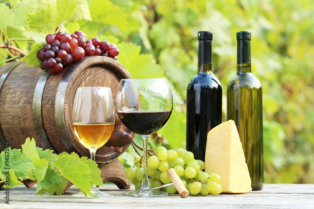 Fototapeta premium Wine in glasses with bunch of grape and cheese on wooden table