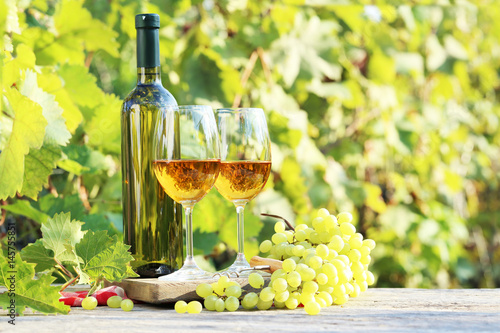 Wine in glasses with bunch of grape on wooden table