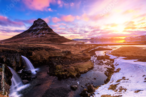 Spring sunrise over the famous Kirkjufellsfoss Waterfall with Kirkjufell mountain in the background in Iceland