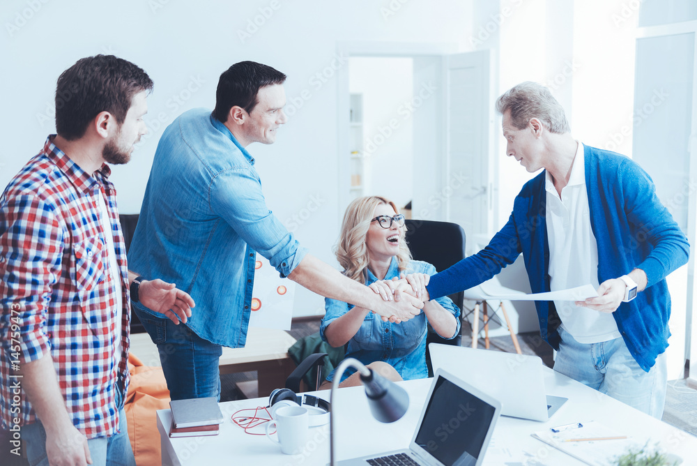 Professional cheerful colleagues holding hands together