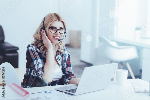 Overjoyed beautiful female support operator sitting in the office