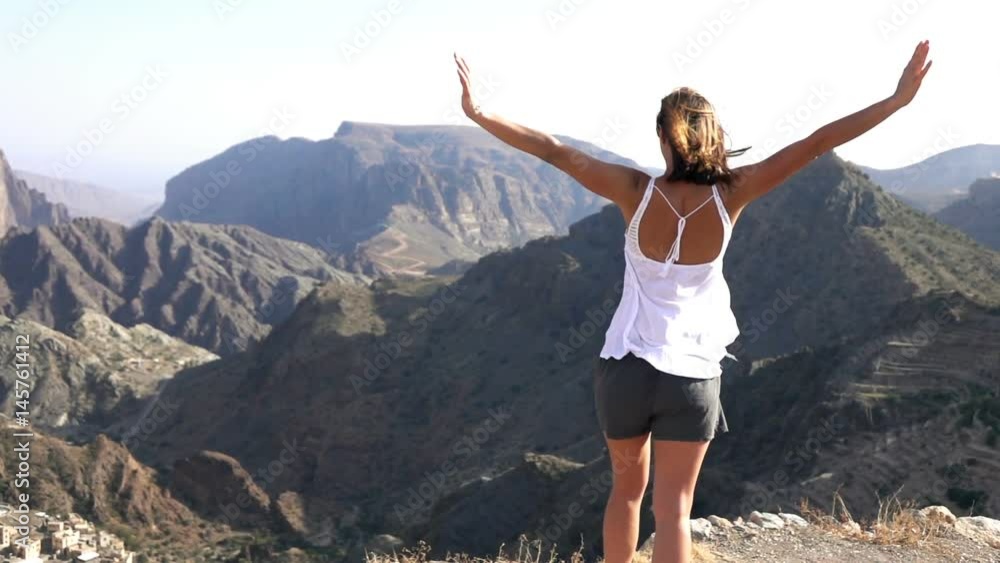 Young woman raising arms in victory standing near canyon, super slow motion 240fps
