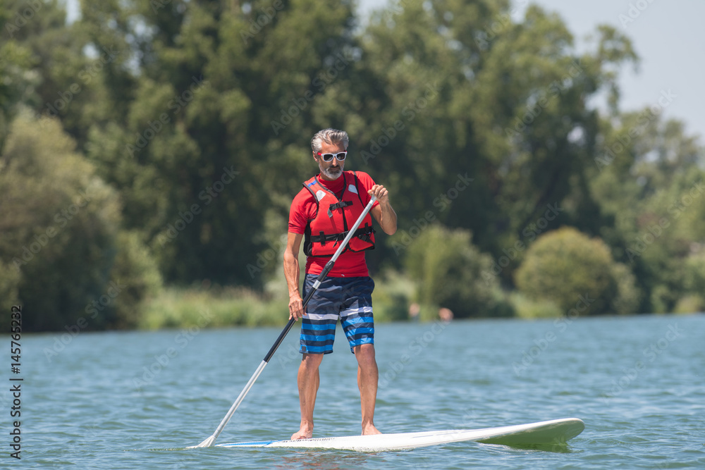 man enjoying a ride on the lake with paddleboard man enjoying a ride on the lake with paddleboard