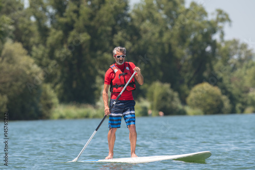 man enjoying a ride on the lake with paddleboard © auremar