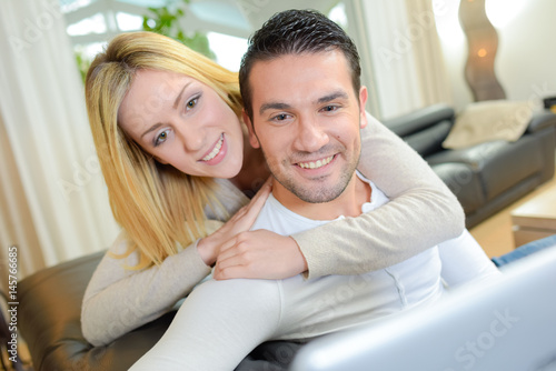 Lady looking at computer screen over man's shoulder
