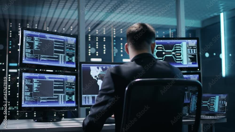 Back View of Technical Controller/ Operator Working at His Workstation with Multiple Displays. Possible Power Plant/ Airport Dispatcher/ Dam Worker/ Government Surveillance/ Space Program Back View of Technical Controller/ Operator Working at His Workstation with Multiple Displays. Possible Power Plant/ Airport Dispatcher/ Dam Worker/ Government Surveillance/ Space Program