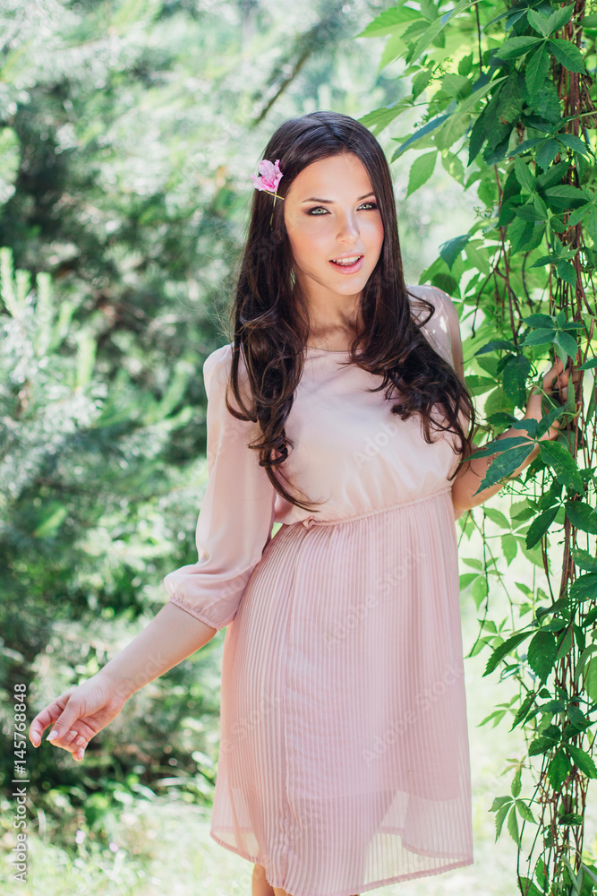 Outdoor fashion photo of beautiful young happy smiling woman surrounded by flowers. Spring blossom Outdoor fashion photo of beautiful young happy smiling woman surrounded by flowers. Spring blossom
