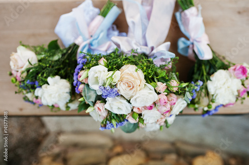 Three wedding bouquets on wooden bench.