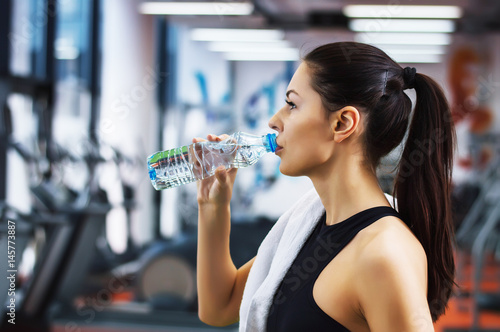 Young woman drinking water in the gym