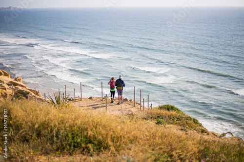 Pacific ocean coast. Cliffs. Flower and plant in the spring. Two people on the cliff